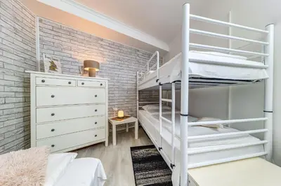 a bedroom with a white bunk bed and a brick wall at Sweet Home Family Lodge at Grand Monastery in Smolyan