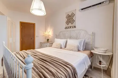 a bedroom with a white bed with a white bedspread at Sweet Home Family Lodge at Grand Monastery in Smolyan