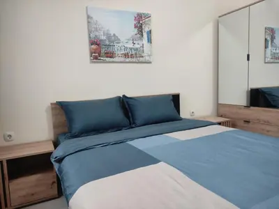 a bedroom with a bed with blue and white sheets at Апартамент за гости НИКОЛОВА in Plovdiv