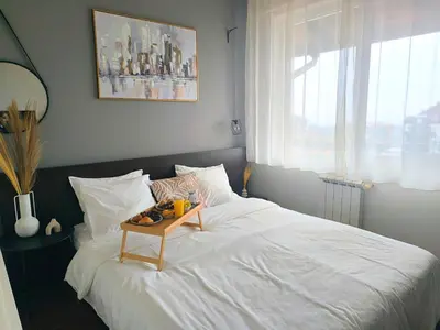 a bedroom with a white bed with a table on it at Urban Atelier 300m from Gondola, Free Bottle of Wine, free Parking in Bansko