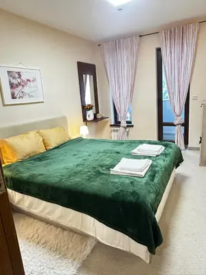 a bedroom with a large green bed with two windows at Green Point Apartment A18 in Pamporovo