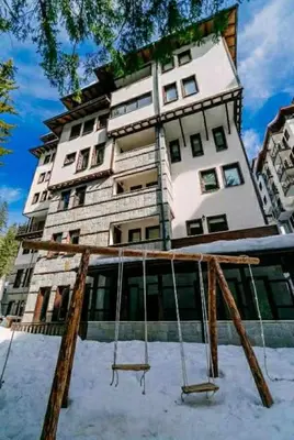 a large building with a swings in front of it at Green Point Apartment A18 in Pamporovo