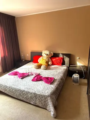a teddy bear sitting on a bed with pink sheets at Ava Apartment Pamporovo in Pamporovo