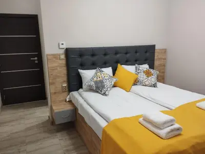 a bedroom with a large bed with yellow sheets and pillows at Странската изба град Калофер in Kalofer