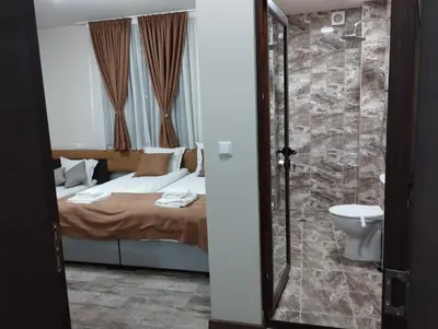 a bedroom with a bed and a shower and a toilet at Странската изба in Kalofer