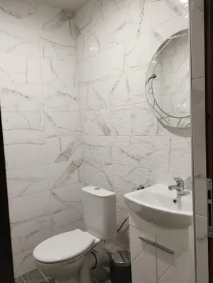 a white bathroom with a toilet and a sink at Странската изба in Kalofer