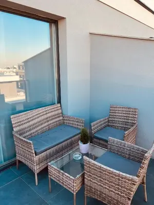three wicker chairs and a table on a balcony at Eternity place in Sofia