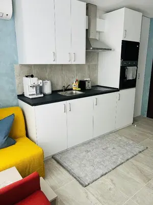 a kitchen with white cabinets and a yellow couch at Eternity place in Sofia