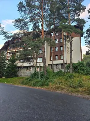 a building on a hill with trees in front of it at Апартамент Kosara 44 in Bansko