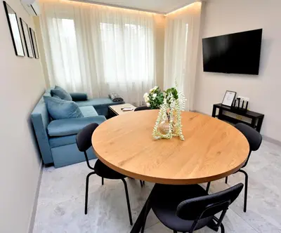 a living room with a table and a blue couch at Contemporary Homes with Balcony in Sofia