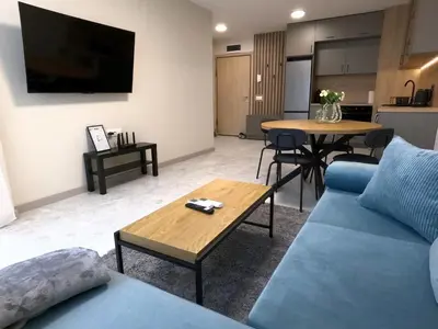 a living room with a blue couch and a table at Contemporary Homes with Balcony in Sofia