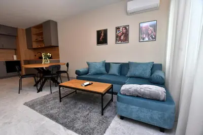 a living room with a blue couch and a table at Contemporary Homes with Balcony in Sofia