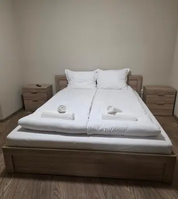 a bed with white sheets and pillows on it at Апартаменти Шадравана in Samokov