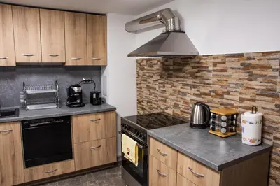 a kitchen with wooden cabinets and a stove top oven at Dzhorgovata Guesthouse in Govedartsi