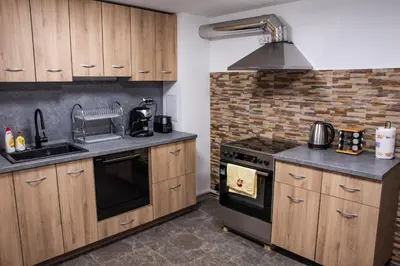 a kitchen with wooden cabinets and a sink and a stove at Dzhorgovata Guesthouse in Govedartsi