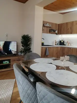 a dining room with a table and chairs and a tv at Уют in Haskovo