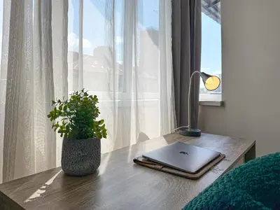 a laptop on a wooden desk next to a window at Heart of Sofia 2 Bdr Elevator Balcony Relax in Sofia