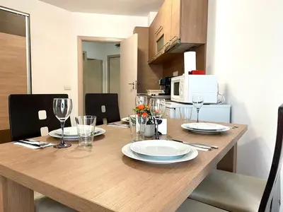 a wooden table with plates and wine glasses on it at Steps from Gondola Private Underground Parking by SI Stay in Bansko