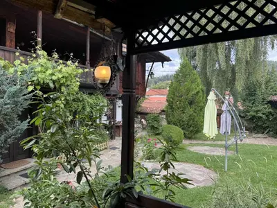 a view of a garden from a porch with a dress on a statue at Мандулова Къща in Koprivshtitsa