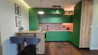 a green kitchen with a counter and some stools at ApArt by the river in Plovdiv
