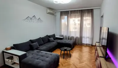 a living room with a black couch and a tv at violet's dream in Plovdiv
