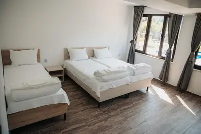a bedroom with two beds and a window at Къща за гости Бели Осъм in Beli Osŭm