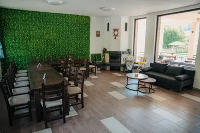 a living room with a green wall and a table and chairs at Къща за гости Бели Осъм in Beli Osŭm