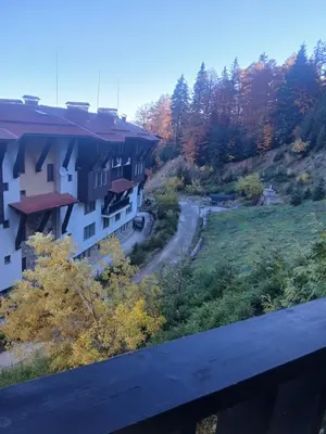 a building on a hill with a road next to it at Grand Monastery apt Emo Pamporovo in Smolyan