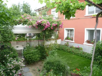 a garden with a pergola with pink flowers at Stai Za Gosti Venera in Hisarya