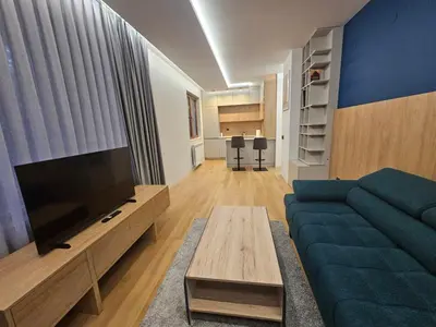 a living room with a blue couch and a flat screen tv at Luxury Forest Apartment in Borovets