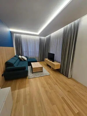 a living room with a blue couch and a television at Luxury Forest Apartment in Borovets