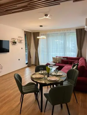 a living room with a table and a red couch at ViVa SPA Retreat in Velingrad