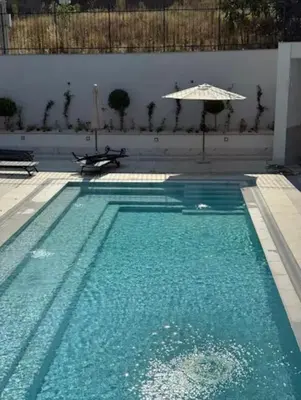 a swimming pool with an umbrella and some water at ViVa SPA Retreat in Velingrad