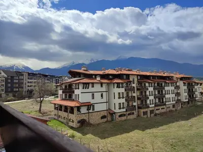 a large apartment building with mountains in the background at Belvedere Holiday Club H70 in Bansko