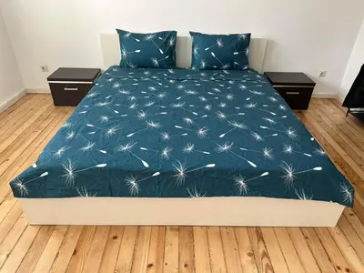 a bed with a blue blanket with dandelions on it at Апартамент 21 in Sofia