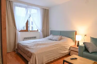 a bedroom with a bed and a chair and a window at Apartment Dream - Comfort & Calm in Pirin Sense by Flat Mаnаger in Bansko