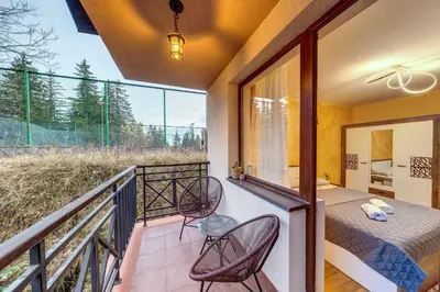 a balcony with two chairs and a table and a bed at Ski-Friendly Family Getaway in Pamporovo