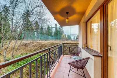 a balcony with two chairs and a view of trees at Ski-Friendly Family Getaway in Pamporovo