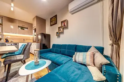 a living room with a blue couch and a kitchen at Ski-Friendly Family Getaway in Pamporovo