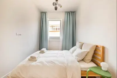a bedroom with a bed and a green chair at Cozy 2BDR Balcony Apt with View in Historic Center in Sofia