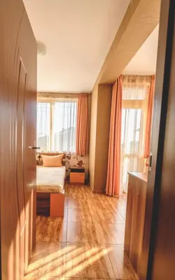 a room with a bed and a bedroom with orange curtains at Къща за гости Бумеранг in Velingrad