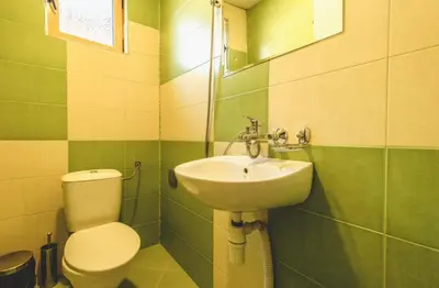a green and white bathroom with a toilet and a sink at Къща за гости Бумеранг in Velingrad