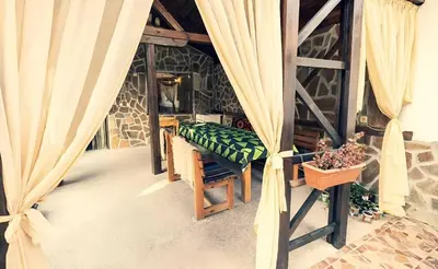 a room with a bed and a table and curtains at Къща за гости Бумеранг in Velingrad