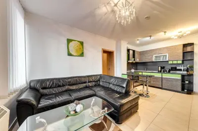 a living room with a leather couch and a kitchen at Alpine Comfort at Grand Monastery in Pamporovo