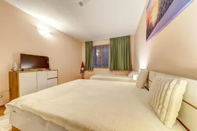 a bedroom with a large white bed and a television at Cozy Evrika 2 Mountain Home in Pamporovo