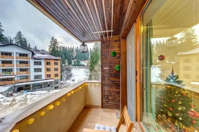 a balcony with a christmas tree and a window at Cozy Evrika 2 Mountain Home in Pamporovo