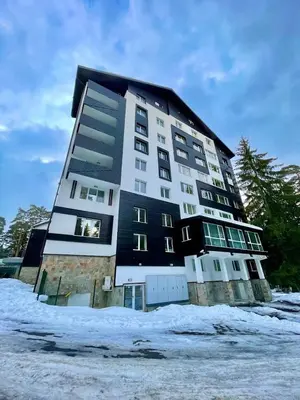 a large building with snow in front of it at Sunlit Forest Suite in Borovets