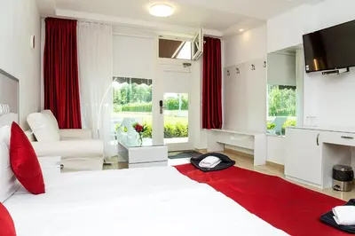 a bedroom with a white bed and a red rug at Complex Europe in Dolna Banya