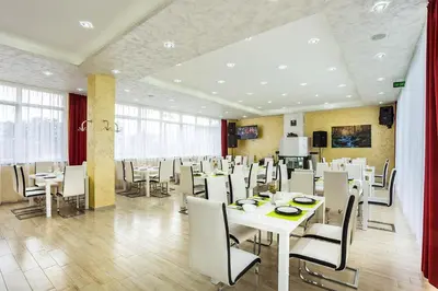 a dining room with white tables and white chairs at Complex Europe in Dolna Banya