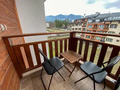 a balcony with chairs and a table and a building at Evergreen Private Apartment 303 in Bansko